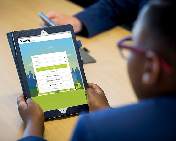 A child in school uniform signing on to Snapplify on a tablet device at school