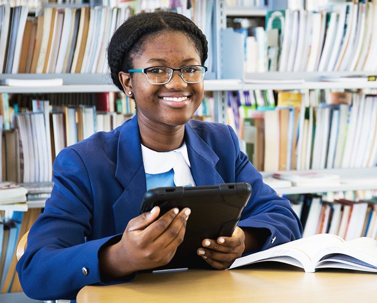 A teenager in at the library in school uniform, accessing her school work using Snapplify on a tablet device